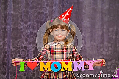 Little cute girl holds a garland with text `I love mommy` of colorful paper alphabet Stock Photo