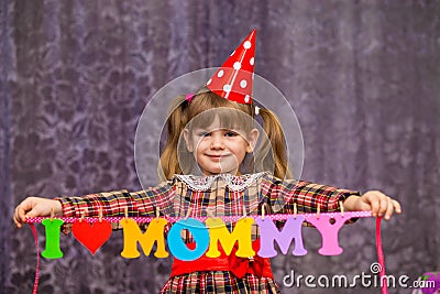 Little cute girl holds a garland with text `I love mommy` of colorful paper alphabet Stock Photo