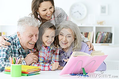 Little cute girl with mother and grandparents studying Stock Photo