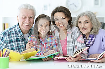 Little cute girl with mother and grandparents studying Stock Photo