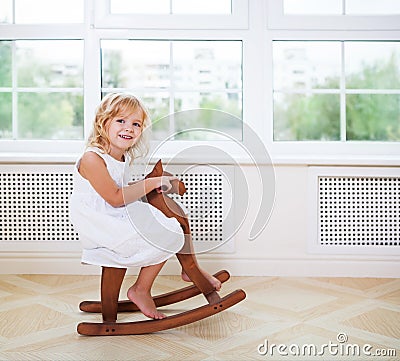 Little cute girl in nursery room with wooden horse Stock Photo