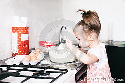 A little cute girl preparing the dough in the kitchen at home Stock Photo