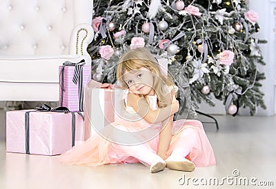 Little cute girl is setting near christmas tree with gifts Stock Photo