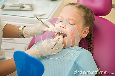 Little cute girl sitting in chair at dentist clinic during dental checkup and treatment, closeup portrait. Stock Photo