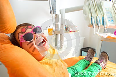 Little cute girl sitting in chair at dentist with sunglasses Stock Photo