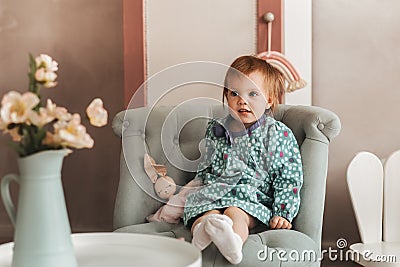 Little cute girl Todler sits in a chair in a children`s room Stock Photo