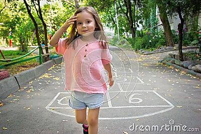 Little cute girl 4 y.o. playing hopscotch on playground outdoors Stock Photo