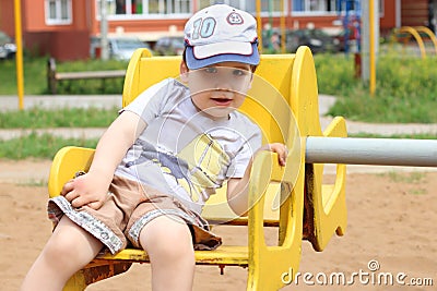 Little cute happy boy rides on carousel on playground Stock Photo