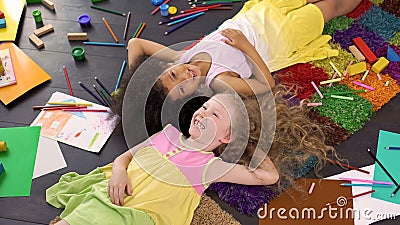 Little cute multiracial friends lying on carpet and laughing, happy childhood Stock Photo