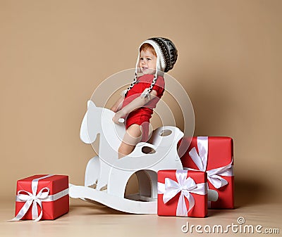 Little smiling baby sitting on a white horse, wooden rocking Stock Photo