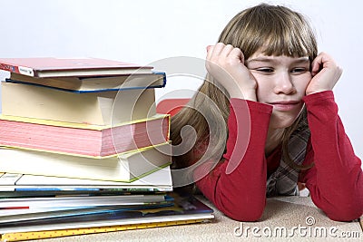 Little cute sad girl with a pile of book sitting Stock Photo
