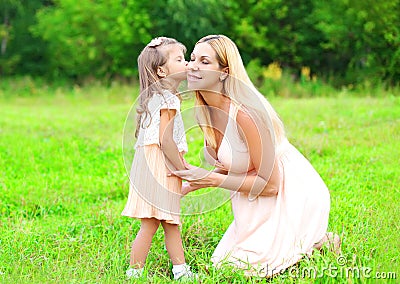 Little daughter child kissing loving mother in summer day, happy family Stock Photo