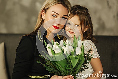 Little daughter give to mother bouquet of flowers. Mom and daughter at home. Bouquet of flowers on 8th of march Stock Photo