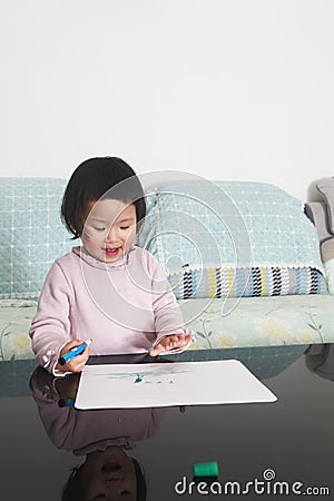 Little daughter using painting stick to scrawl Stock Photo