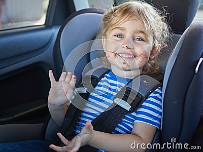 Little dirty girl , baby in a safety car seat. Stock Photo