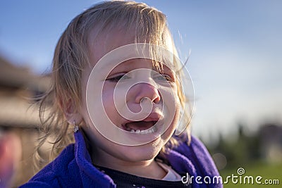 Little disheveled girl crying outdoors Stock Photo