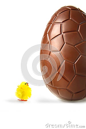 Little easter chick looking up at chocolate egg Stock Photo