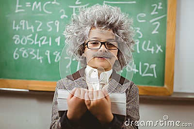 Little Einstein holding books in front of chalkboard Stock Photo
