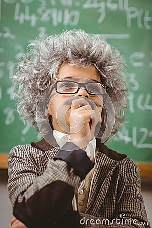 Little Einstein thinking in front of chalkboard in a classroom Stock Photo