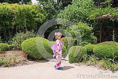 Little european girl in japanese kimono in japanese little garden. Japanese kimno on european girl Stock Photo