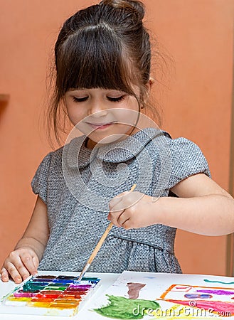 Little european girl painting at table indoors. Stock Photo