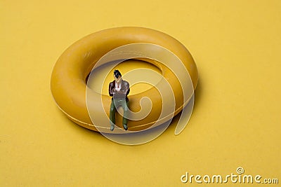 Little figurine man sitting on a life preserver Stock Photo