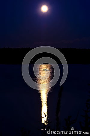 Little fishing boot on the river at night lit by the full moon Stock Photo