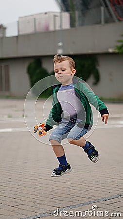 Little funny boy jumps on the square with gray pavement Stock Photo
