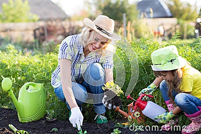 Little gardener girl with mother watering on lawn near house Stock Photo