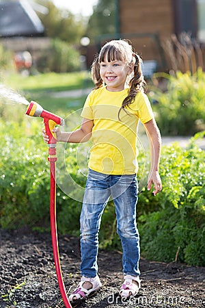 Little gardener girl watering with hosepipe Stock Photo