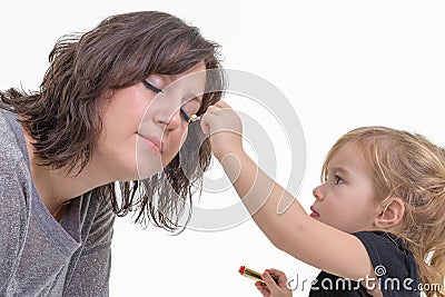 Little girl applying makeup to her mother Stock Photo