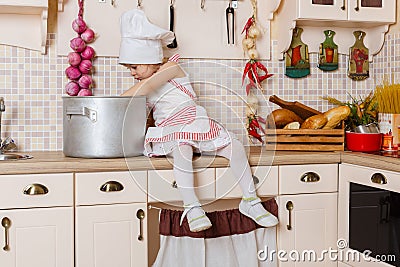 Little girl in apron in the kitchen. Stock Photo