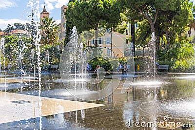 A little girl in a bathing suit plays in the water fountain spray at the Paillon Promenade in the city of Nice, France Editorial Stock Photo