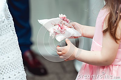 Little girl in a beige dress holding ring for the bride for the wedding ceremony in church Stock Photo