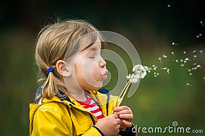 Little girl blowing on dandelion. Future generation. Windmills. Renewable energies and sustainable resources - wind Stock Photo