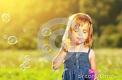 Little girl blowing soap bubbles in nature Stock Photo