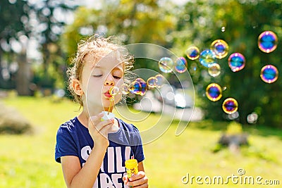 A little girl blowing soap bubbles in summer park. Stock Photo