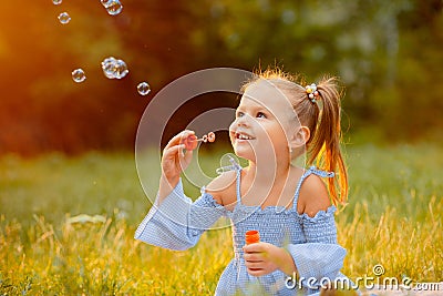 A little girl blows soap bubbles Stock Photo