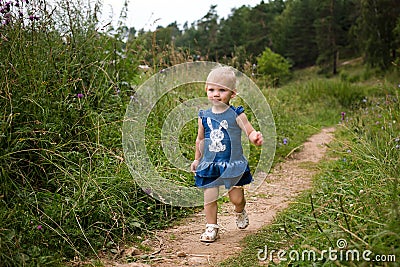 A little girl walks alone along the path. Summer day, wildflowers Stock Photo