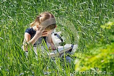 Little girl with a book in the garden. Kid is readding a book. A little girl 4-5 years old sits on the grass and reads a book Stock Photo