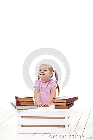 Joyful little girl with books sits on a white floor. Stock Photo