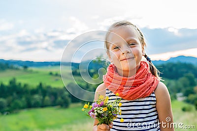 little girl with a bouquet of wild flowers on a background of a Stock Photo