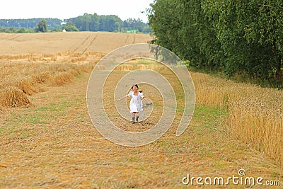 Little girl with a bouquet of wildflowers in her hands in a wheat field. Stock Photo