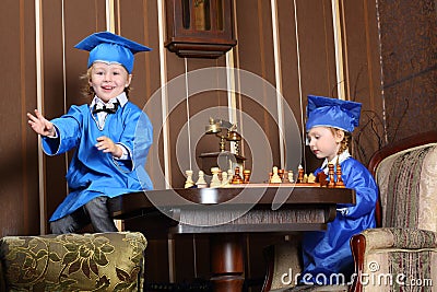 Little girl and boy in blue suits play chess Stock Photo