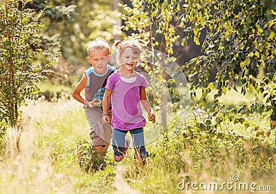 Little girl and boy playing together in sunny summer garden Stock Photo