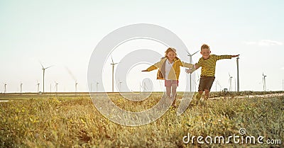 Little girl and boy are running in front of windmills. Renewable energies and sustainable resources - wind mills Stock Photo