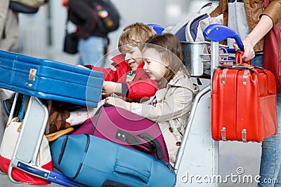 Little girl and boy sitting on suitcases on airport Stock Photo