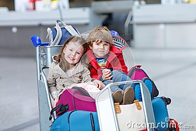 Little girl and boy sitting on suitcases on airport Stock Photo