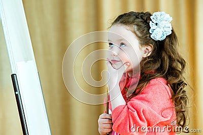 Little girl with a brush at the easel thinks about the future drawing. Beautiful model 4-5 years Stock Photo