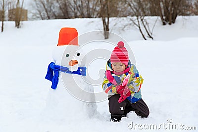 Little girl building snowman in nature Stock Photo